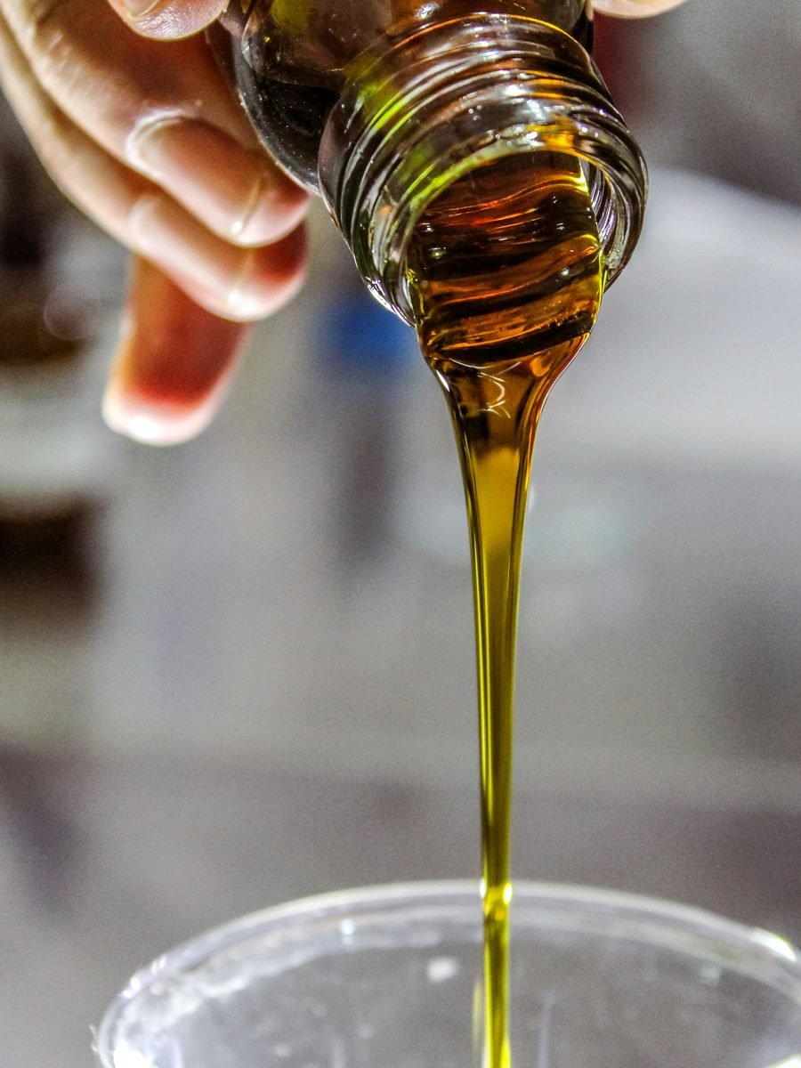 Aceite de oliva cayendo desde una botella a un vaso de vidrio